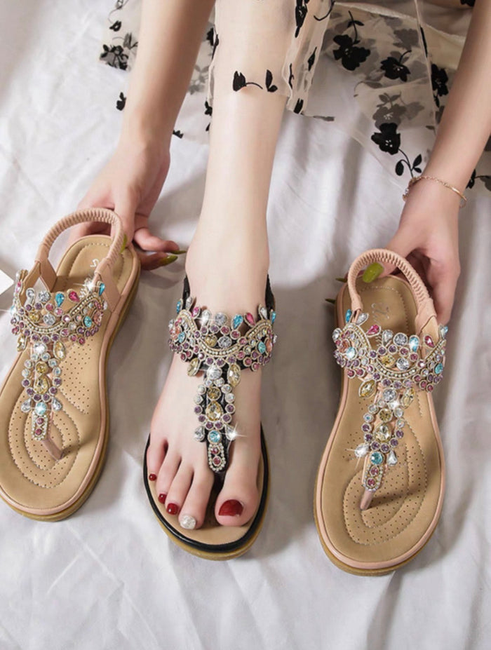 Bejeweled sandals worn by a person on a white surface