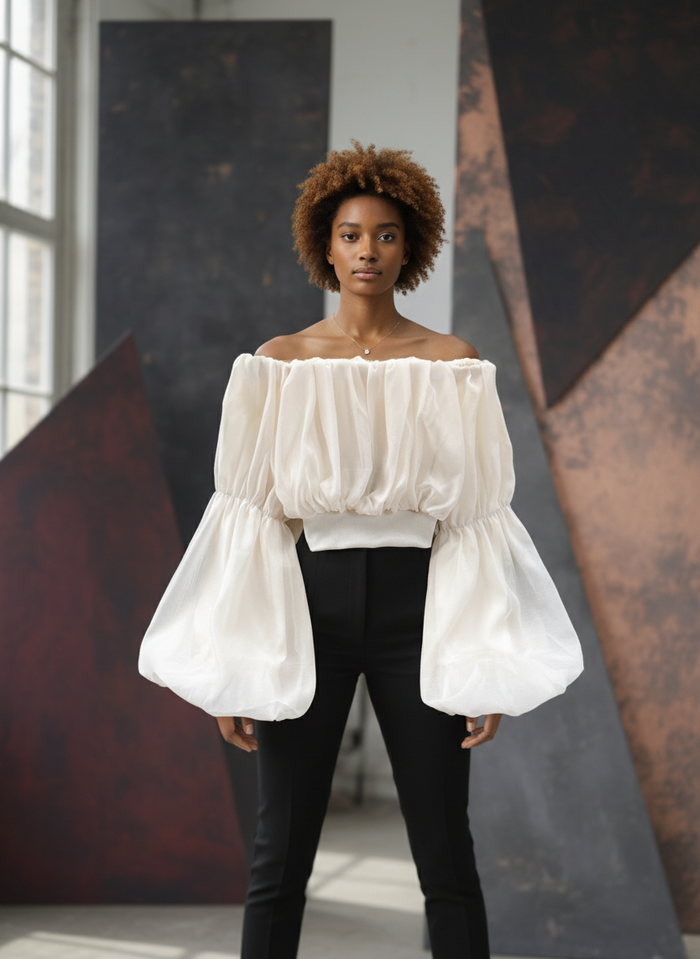 Woman wearing a white off-shoulder top with puffed sleeves in an indoor setting.