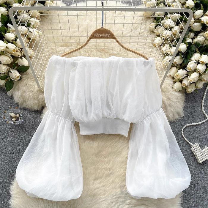 White blouse with ruffled sleeves on a hanger against a decorative background with flowers and fur.