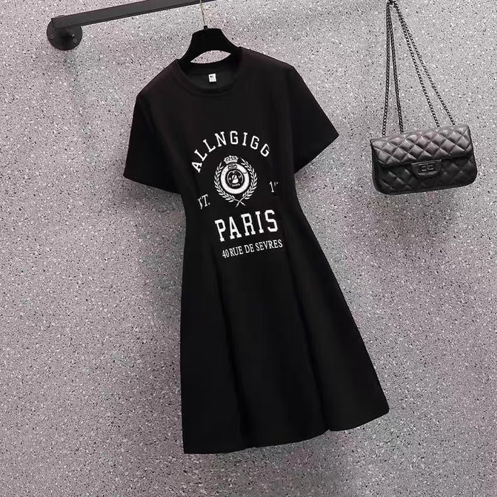 Black dress with white text and design on a textured gray surface next to a black handbag.