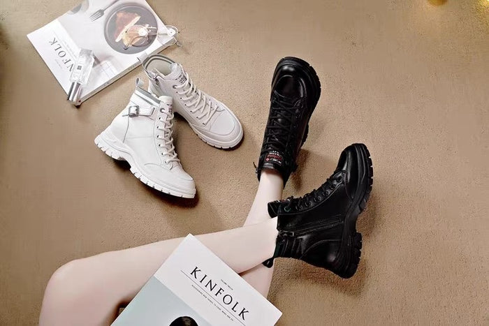 White and black boots on a beige surface with books underneath.