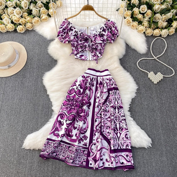 Purple and white patterned dress on a hanger with flowers and jewelry around
