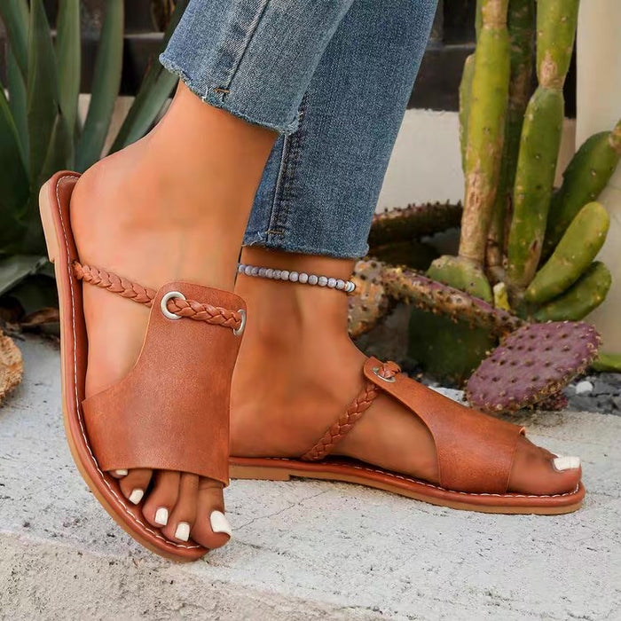 Brown leather sandals worn with rolled-up jeans against a cactus background