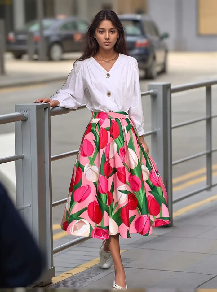 Woman wearing a white blouse and colorful floral skirt on a city street.